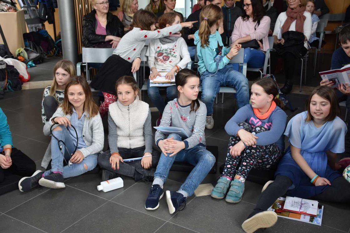 Kindergruppe bei Projektveranstaltung im Krankenhaus Martha-Maria, sitzend mit Schreibmaterialien.