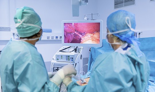 Chirurgen betrachten Monitor während einer minimalinvasiven Operation im OP-Saal.