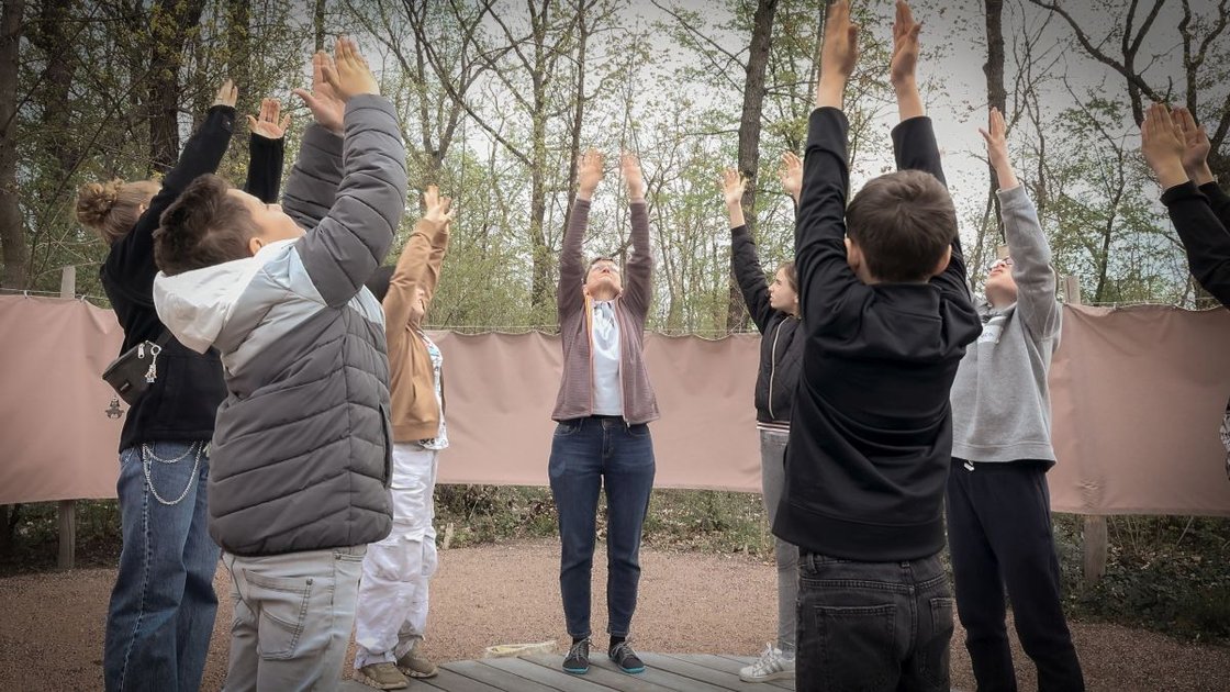 Kinder und Erwachsene machen Dehnübungen im Freien im Rahmen eines Bildungsprojekts.