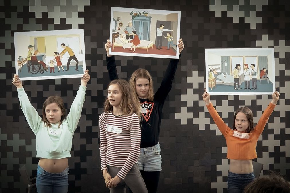 Vier Kinder präsentieren Illustrationen von Krankenhaus-Szenen während eines Bildungsprojekts.