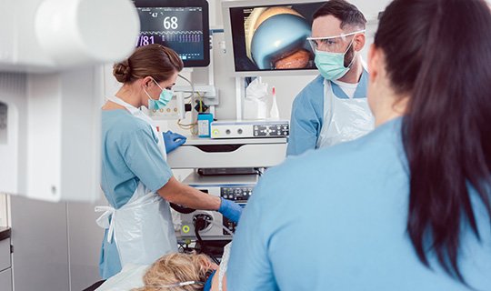 Ärzte in Schutzkleidung führen medizinische Prozedur mit Monitorüberwachung durch.