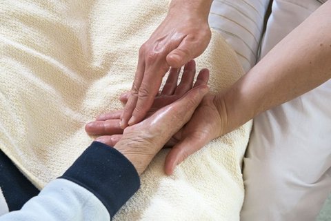 Pflegekraft hält die Hand eines Patienten auf der Palliativstation.