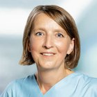 Porträt einer lächelnden Frau in medizinischer Berufskleidung.