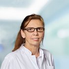 Porträt einer Frau in Arztkittel vor einem unscharfen Hintergrund.