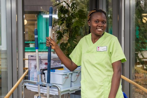 Pflegerin in grüner Uniform mit Reinigungswagen in einem Krankenhaus.