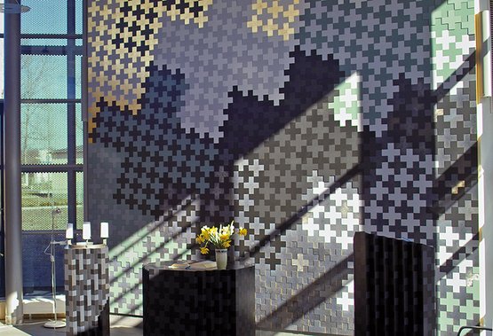 Innenraum der Dietrich-Bonhoeffer-Kapelle mit bunter Mosaikwand und Sonnenlicht.