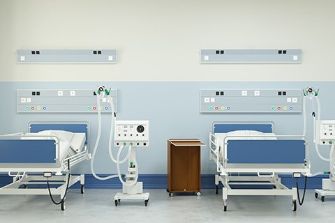 Zwei Krankenhausbetten mit medizinischer Ausrüstung in einem hellen Raum.