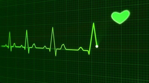 Grüner EKG-Monitor zeigt Herzfrequenz mit Herzsymbol.