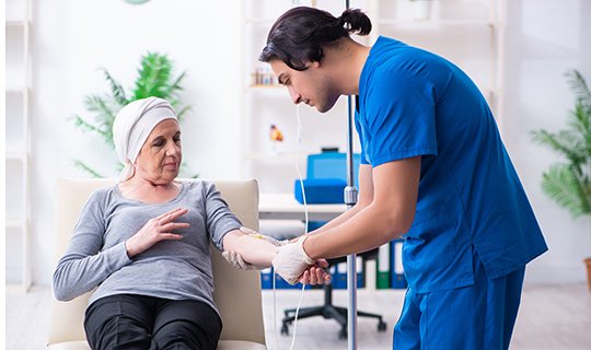 Pflegekraft legt Patientin mit Kopftuch eine Infusion an, symbolisiert medizinische Betreuung.