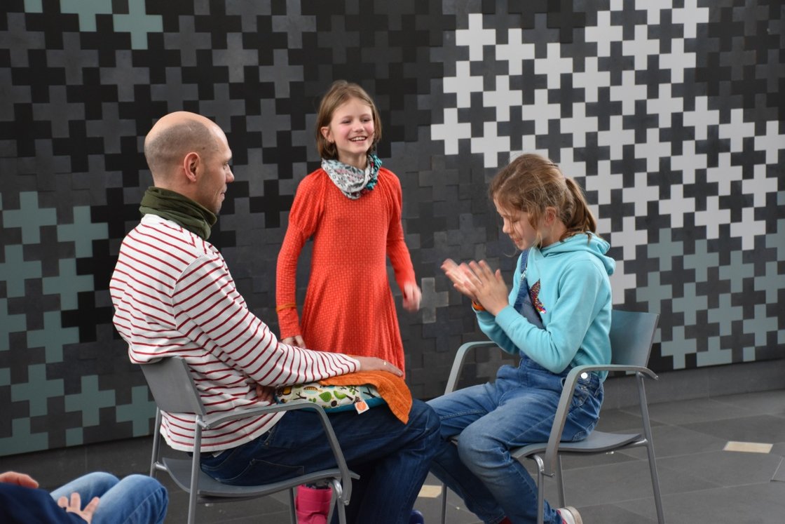 Kinder und Erwachsener interagieren fröhlich bei Bildungsprojekt im Krankenhaus.