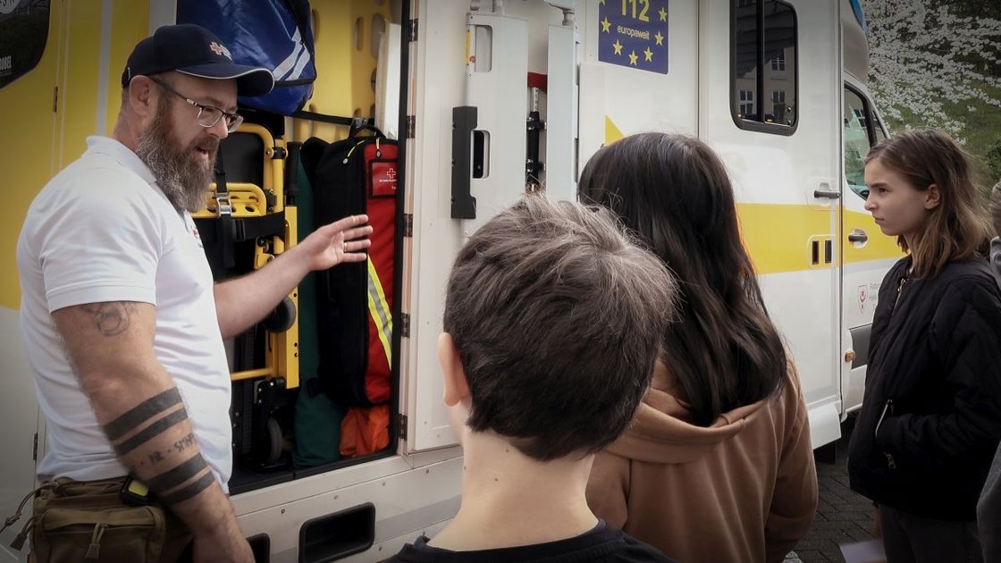 Sanitäter erklärt Kindern Krankenwagenausrüstung während des Projekts Jonas will's wissen.