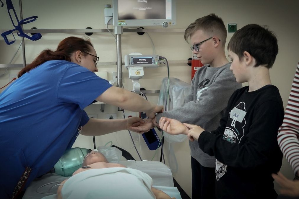 Pflegekraft zeigt Kindern im Krankenhaus medizinische Ausrüstung.