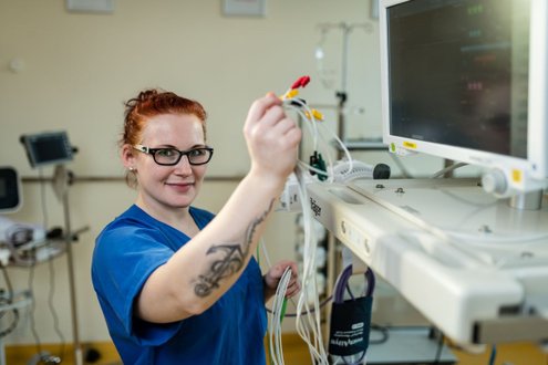 Pflegekraft in blauer Uniform arbeitet am medizinischen Monitor.
