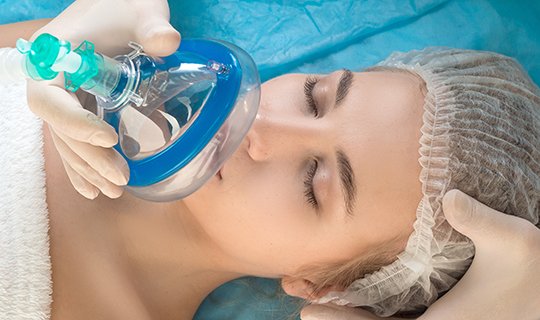 Patientin erhält Anästhesie mit Gesichtsmaske vor medizinischem Eingriff.