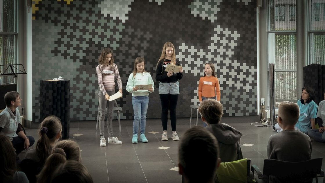 Vier Kinder präsentieren ein Projekt vor Publikum im Krankenhaus Martha-Maria.