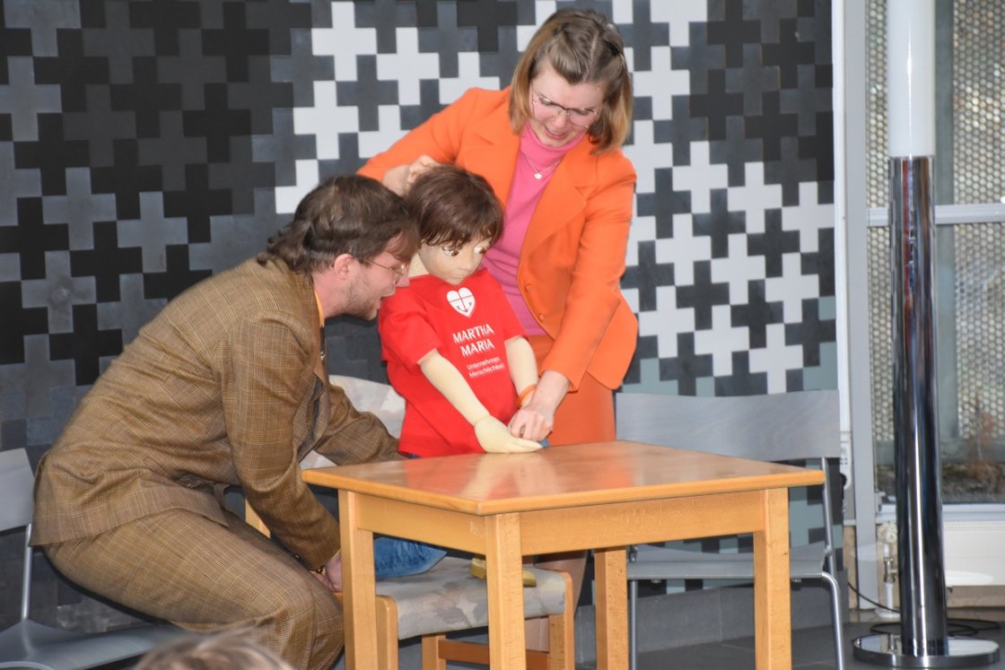 Zwei Erwachsene zeigen einem Kind eine Puppe beim Projekt im Krankenhaus Martha-Maria.