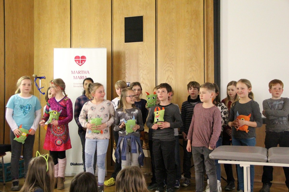Kinder präsentieren bunte Stoffpuppen bei Projektvorstellung im Krankenhaus Martha-Maria.
