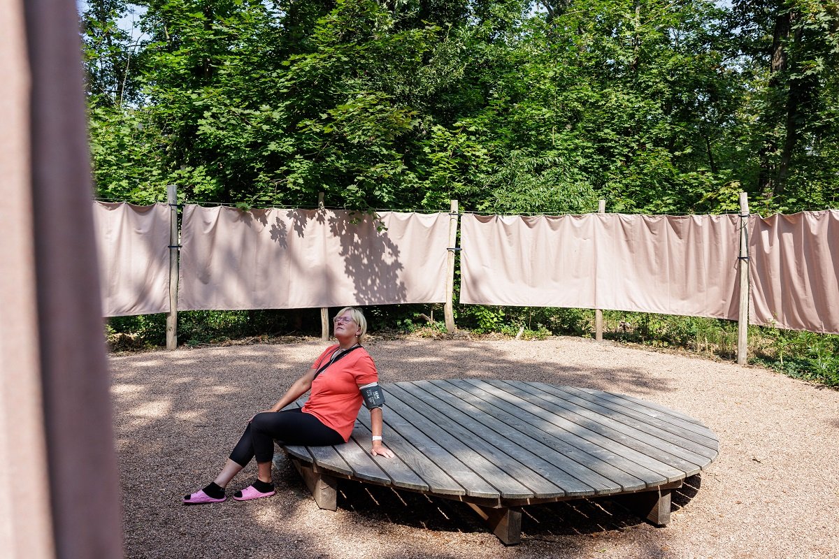 Frau entspannt auf Holzplattform in besinnlichem Krankenhausgarten.