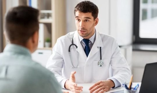 Arzt im Gespräch mit einem Patienten im Krankenhausbüro.