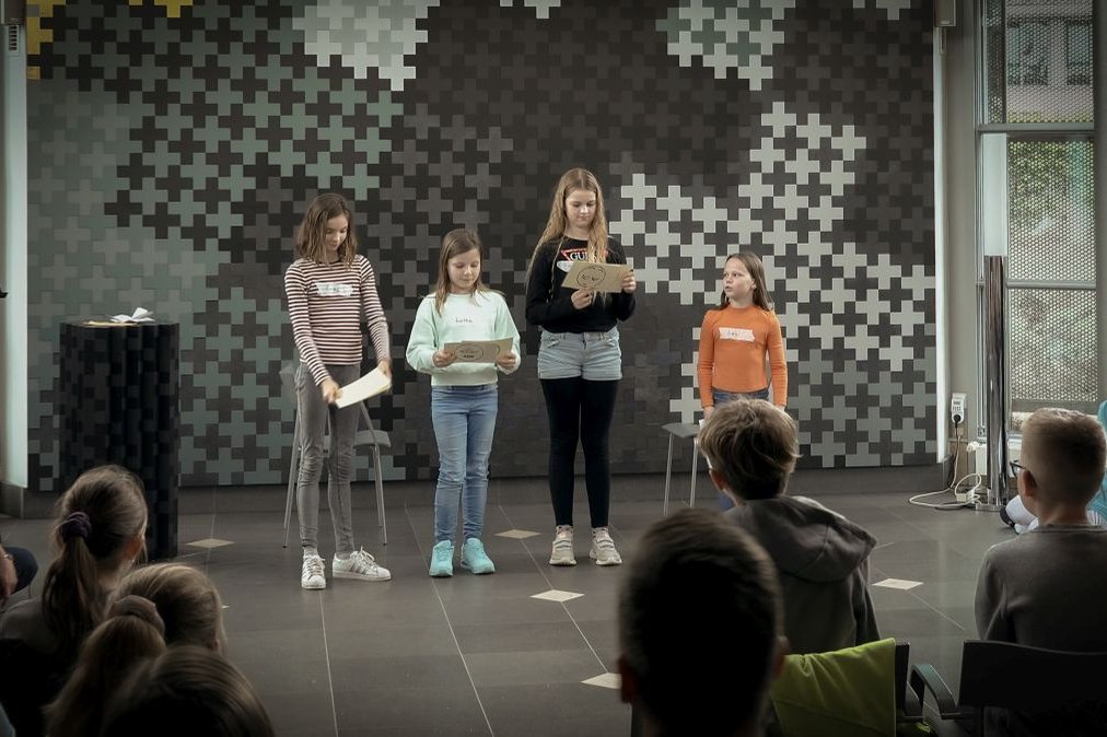 Vier Kinder präsentieren ein Projekt vor Publikum im Krankenhaus Martha-Maria.