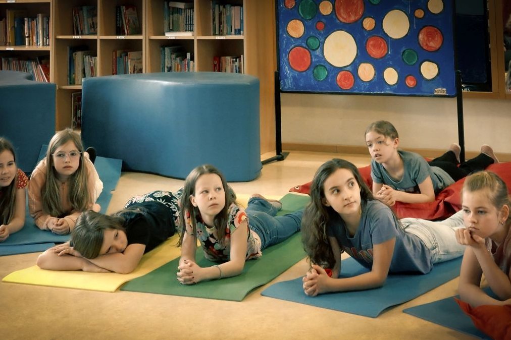 Kindergruppe liegt auf Matten, aufmerksam bei Bildungsprojekt im Krankenhaus.