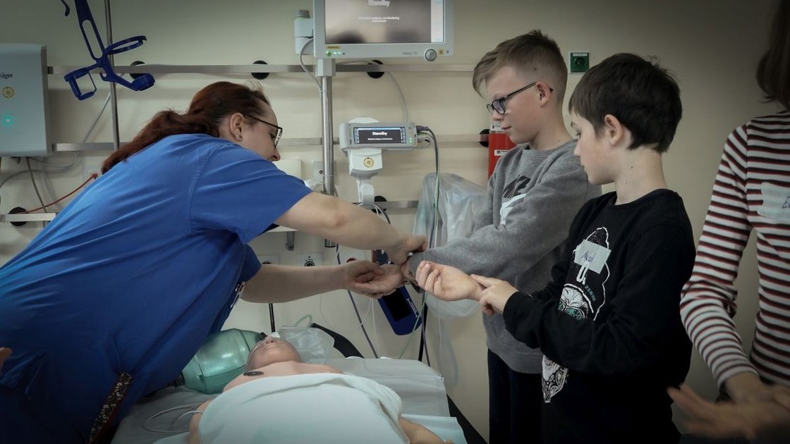 Pflegekraft zeigt Kindern im Krankenhaus medizinische Ausrüstung.