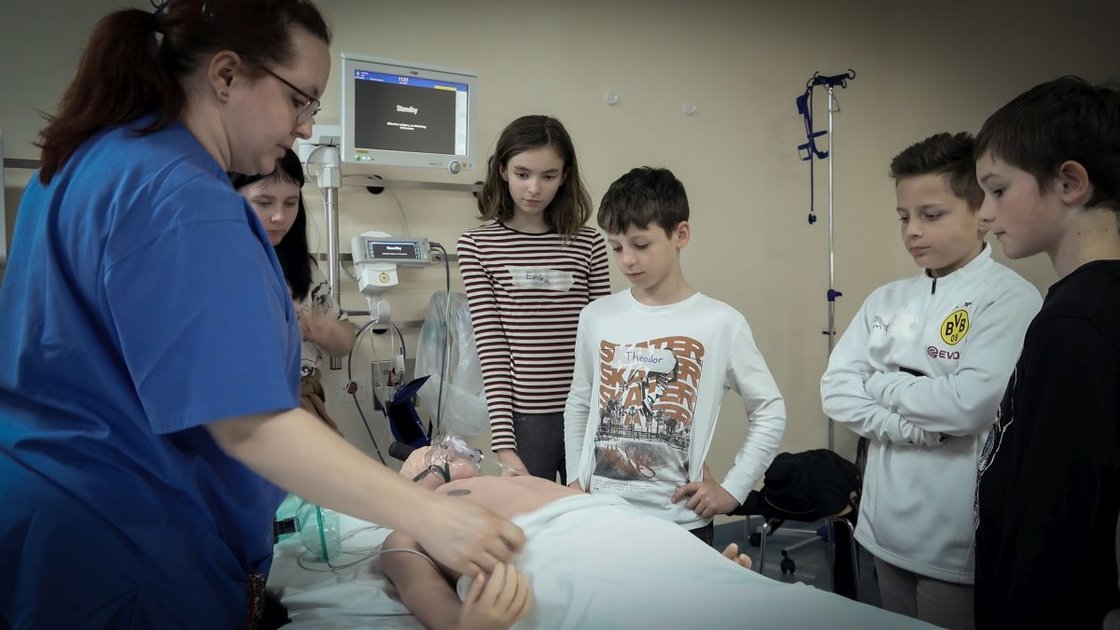 Kindergruppe beobachtet Krankenschwester bei Demonstration im Krankenhaus Martha-Maria.