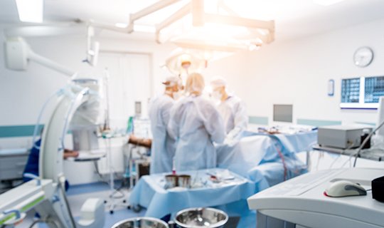 Ärzte in OP-Kleidung führen Operation im modernen Krankenhaus durch.