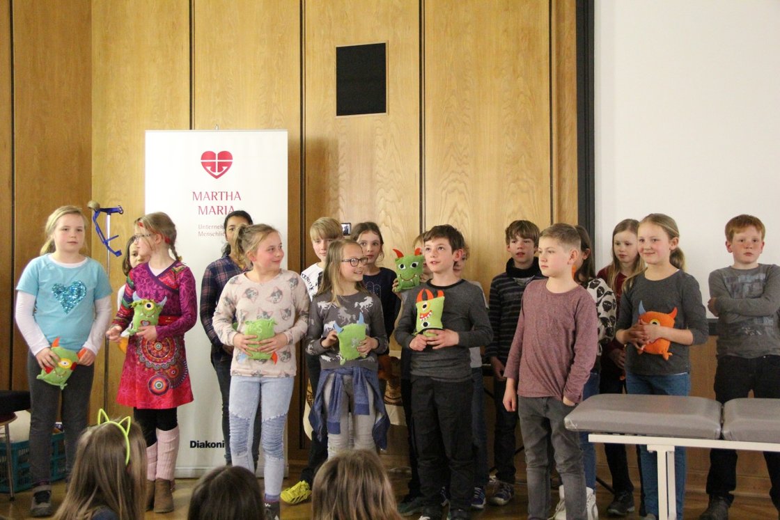 Kinder präsentieren bunte Stoffpuppen bei Projektvorstellung im Krankenhaus Martha-Maria.