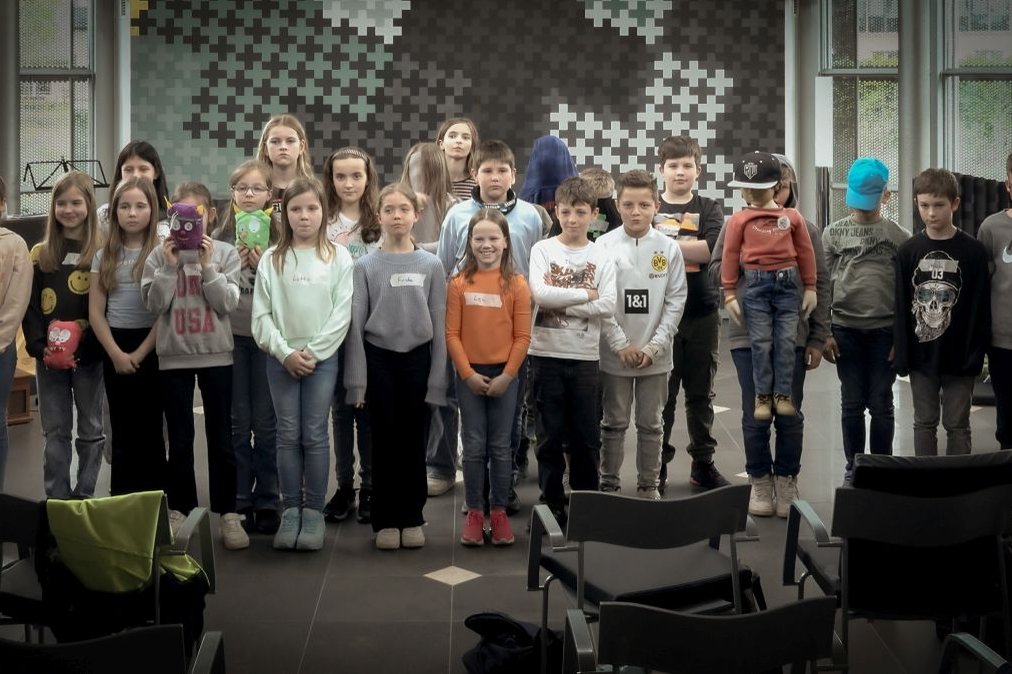 Eine Gruppe Kinder präsentiert stolz selbstgemachte Puppen im Krankenhaus Martha-Maria.