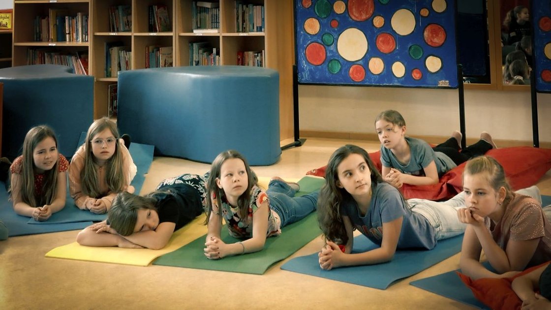 Kindergruppe liegt auf Matten, aufmerksam bei Bildungsprojekt im Krankenhaus.