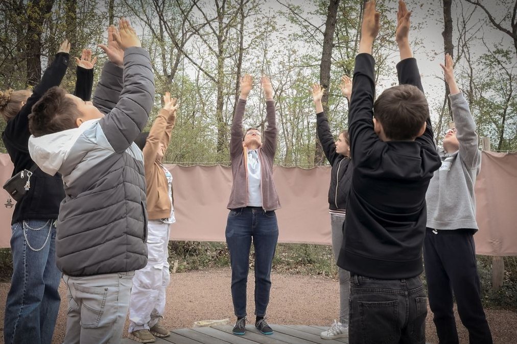 Kinder und Erwachsene machen Dehnübungen im Freien im Rahmen eines Bildungsprojekts.