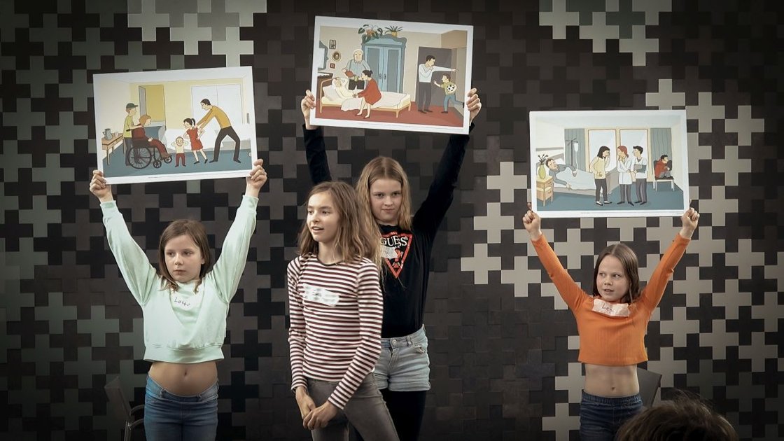 Vier Kinder präsentieren Illustrationen von Krankenhaus-Szenen während eines Bildungsprojekts.